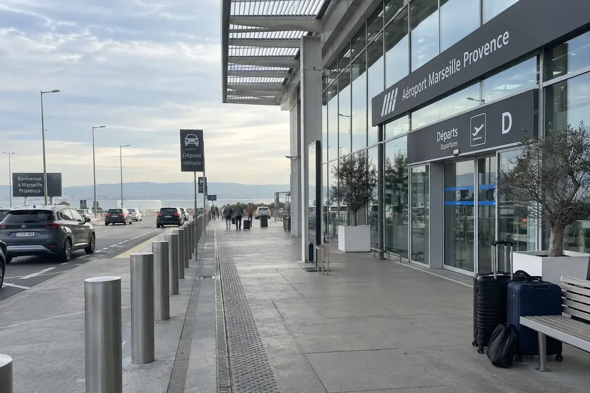 Le trottoir des départs de l’aéroport Marseille-Provence à Marignane, valises au pied d’un banc