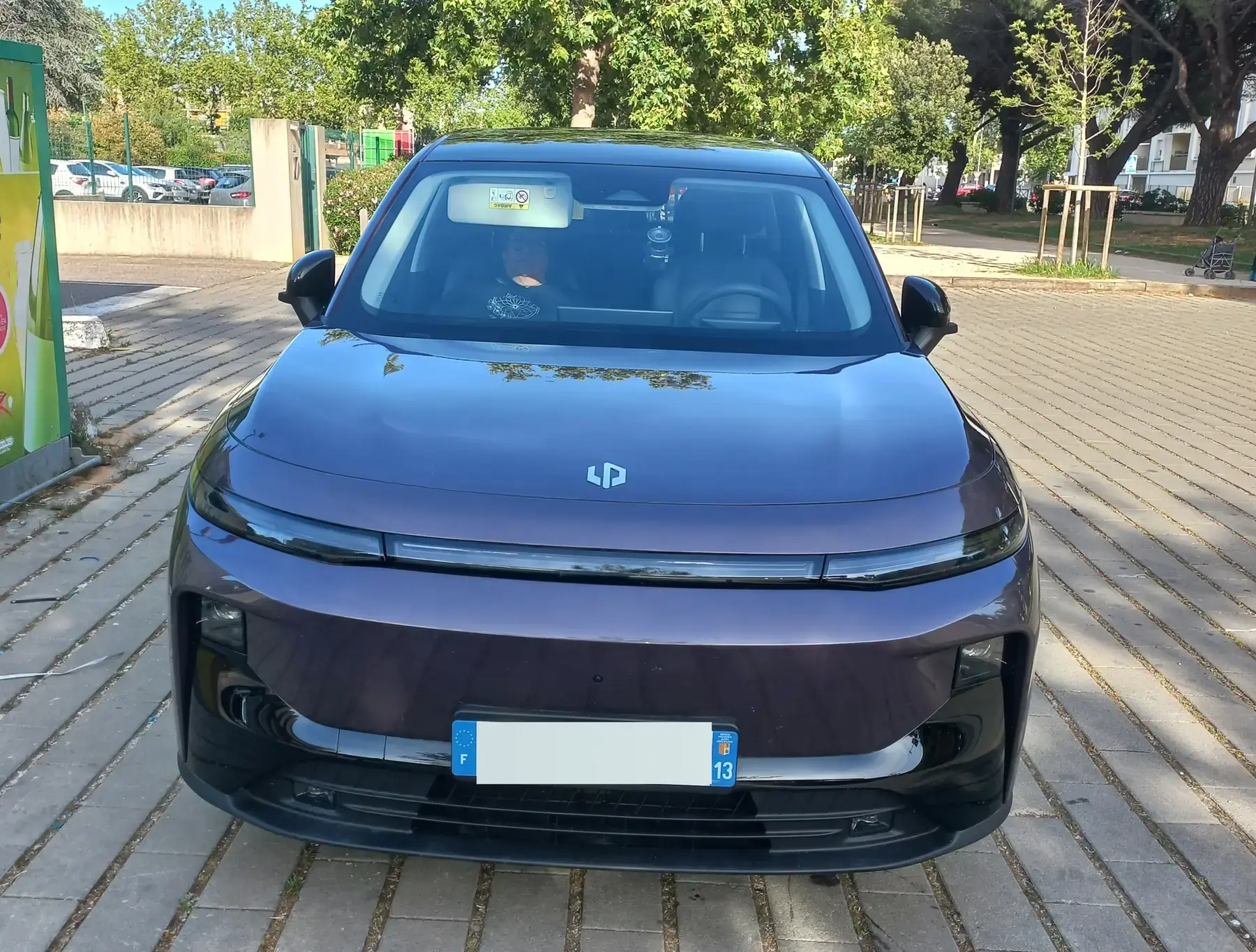 La Leapmotor B10 pourpre de Dominique vue de face, au soleil sous les platanes