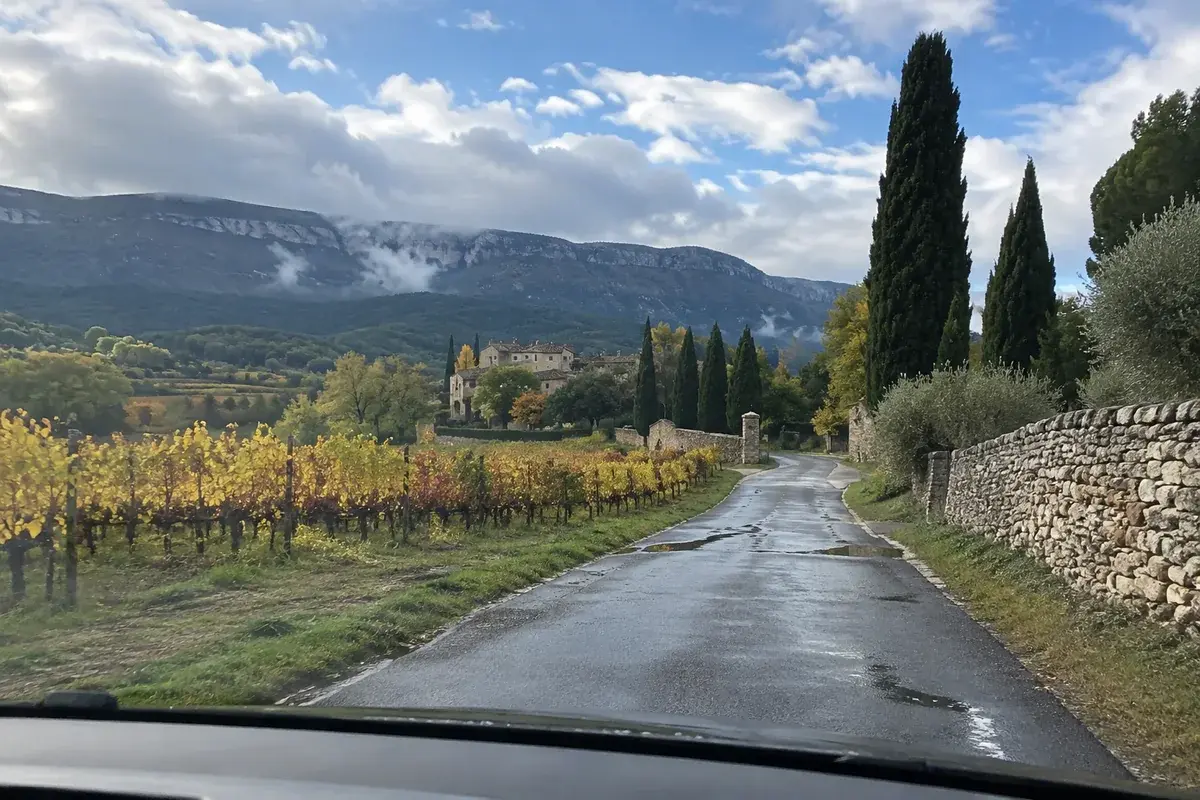 Une petite route entre les vignes du Luberon après la pluie, la montagne dans les nuages